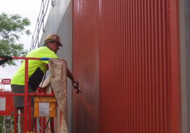 Worker Applying Lithium Concrete Coating On Red Industrial Wall Worker Applying Lithium Concrete Coating On Red Industrial Wall