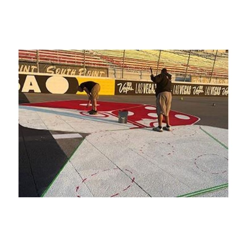 Person Applying Red Paint On Pavement Using Spray Equipment